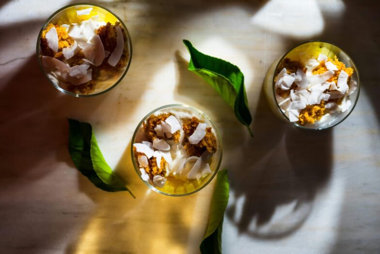 Top view of dessert with coconut shards, leaves, and shadows creating a warm ambiance.