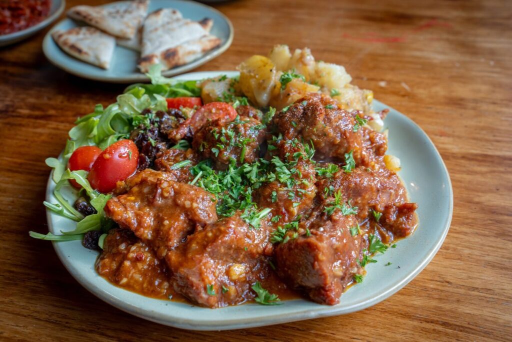 Savor a hearty beef stew with fresh cherry tomatoes and greens, perfect for lunch.