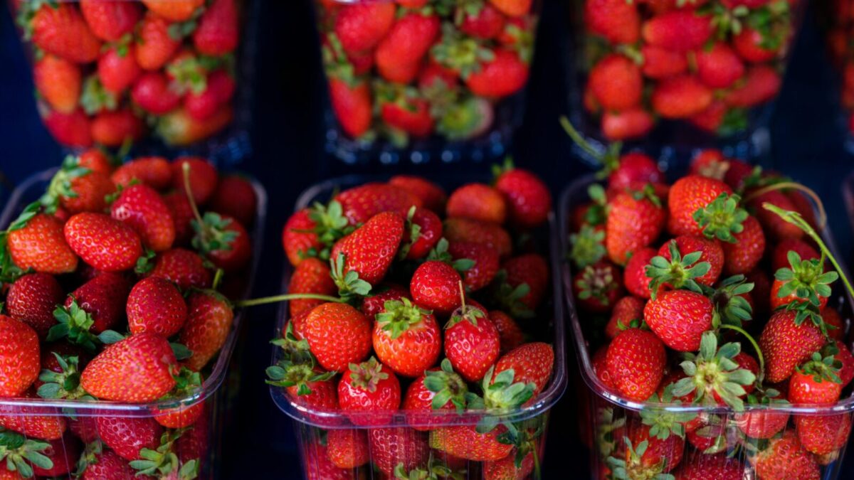 Bright and juicy red strawberries arranged in plastic containers at a farmers' market.