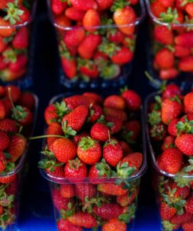 Bright and juicy red strawberries arranged in plastic containers at a farmers' market.