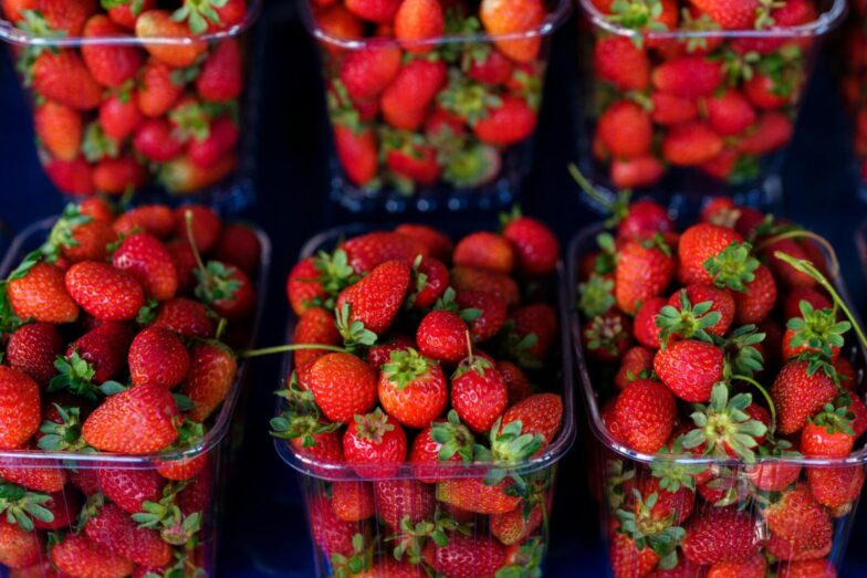 Bright and juicy red strawberries arranged in plastic containers at a farmers' market.