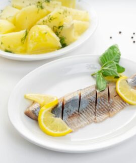 Delicious fish fillet with lemon slices and herb potatoes on white plates.