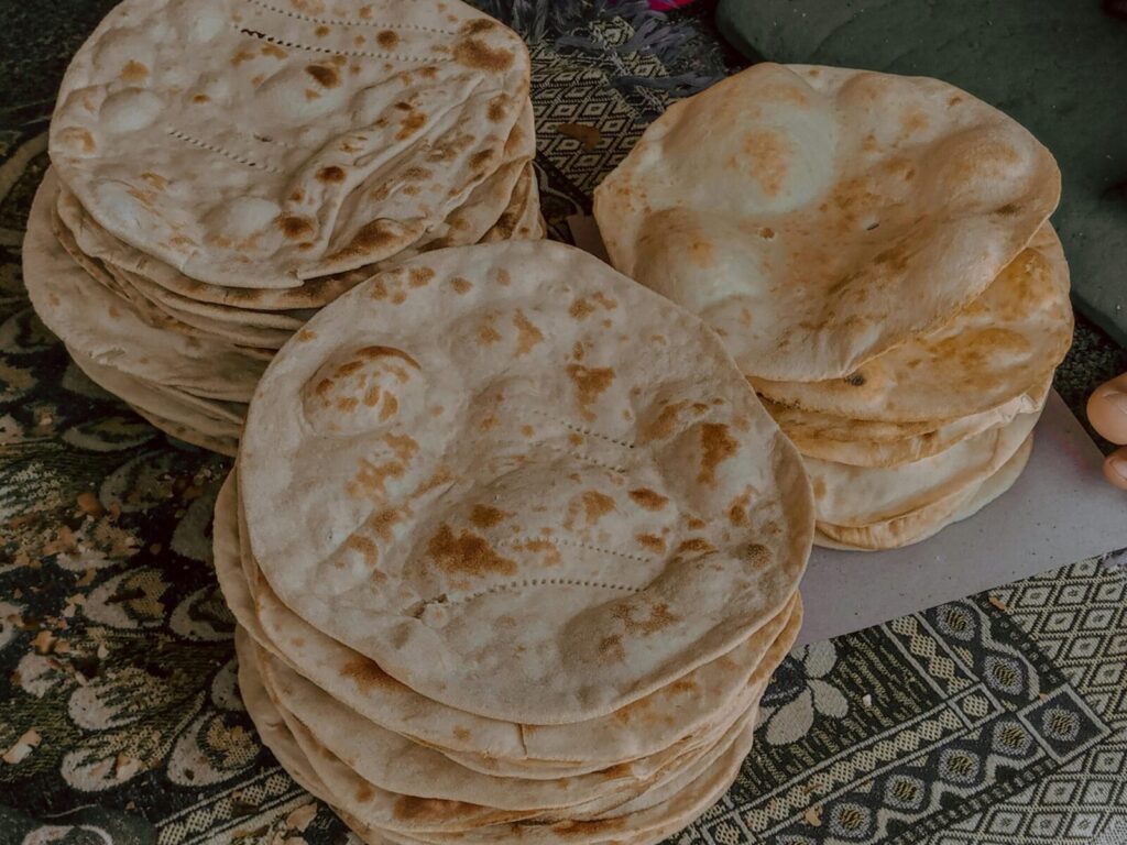 Freshly baked flatbreads neatly stacked on a patterned cloth, captured from above.