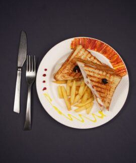 Delicious grilled toast and fries plated elegantly, shot in a studio on a black background.