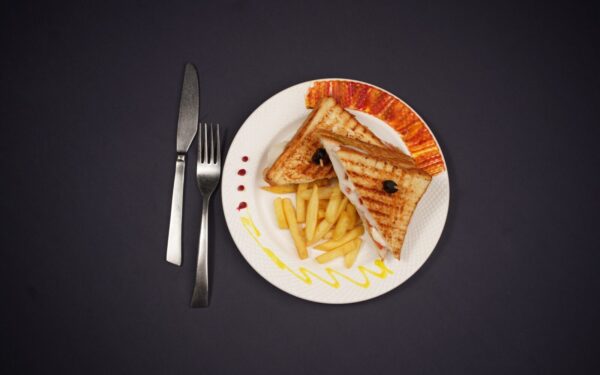 Delicious grilled toast and fries plated elegantly, shot in a studio on a black background.