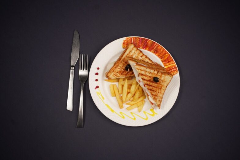 Delicious grilled toast and fries plated elegantly, shot in a studio on a black background.
