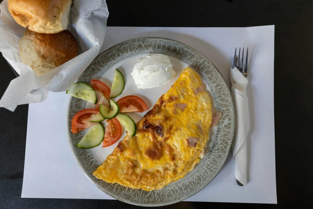 Appetizing breakfast featuring a cheesy omelet, salad, and fresh rolls.
