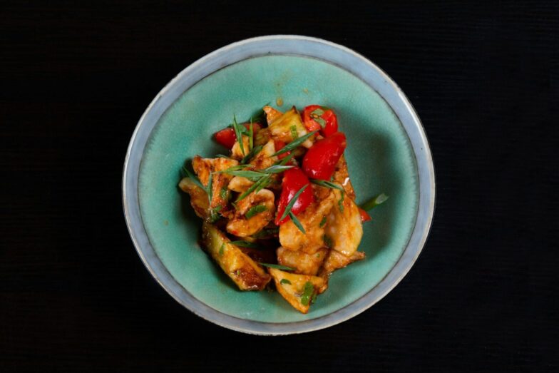 Delicious spicy chicken stir fry with colorful peppers served in a bowl. Perfect for a flavorful meal.