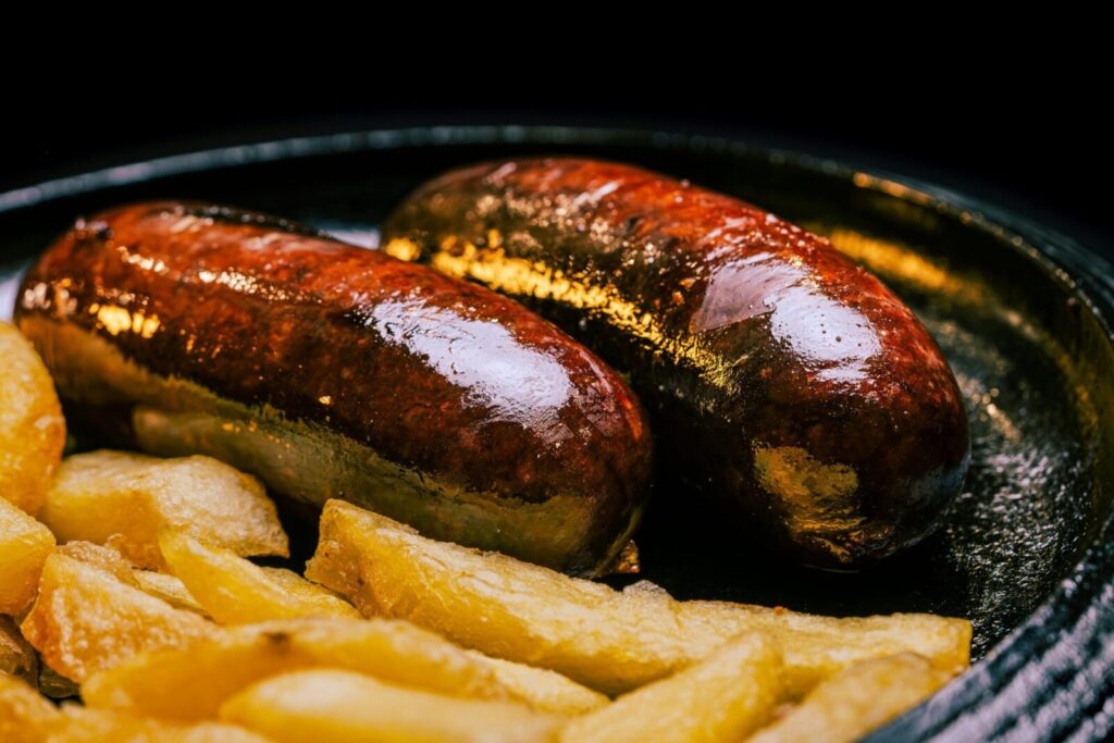 Close-up of sizzling sausages paired with crispy fries, perfect for a hearty meal.