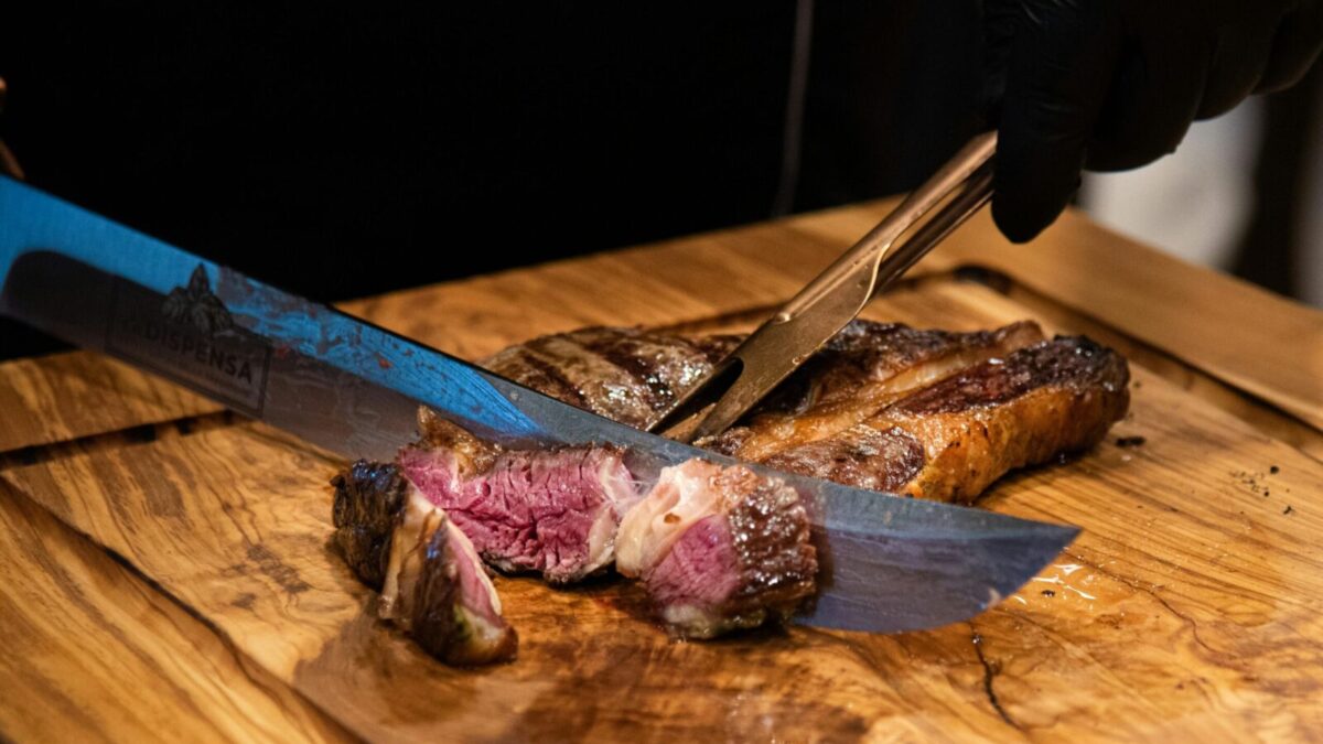 Close-up of a juicy grilled steak being sliced with a knife, showcasing its tender texture and delicious appearance.