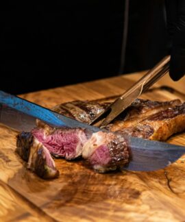 Close-up of a juicy grilled steak being sliced with a knife, showcasing its tender texture and delicious appearance.