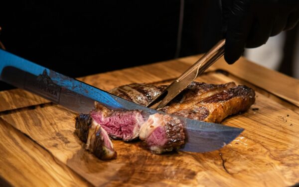 Close-up of a juicy grilled steak being sliced with a knife, showcasing its tender texture and delicious appearance.