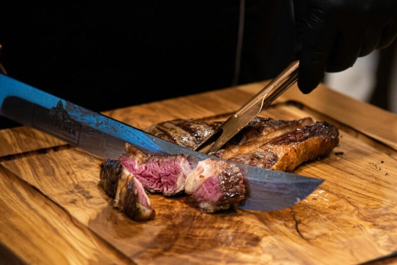 Close-up of a juicy grilled steak being sliced with a knife, showcasing its tender texture and delicious appearance.
