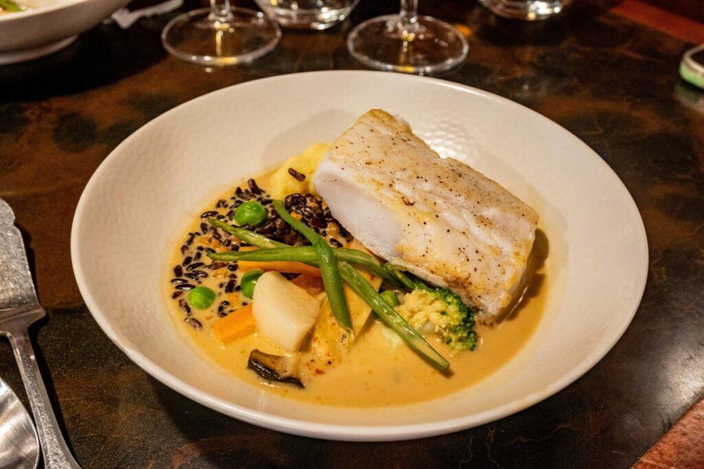 A delicious gourmet seafood dish featuring cod, vegetables, and creamy sauce.