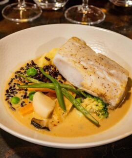 A delicious gourmet seafood dish featuring cod, vegetables, and creamy sauce.