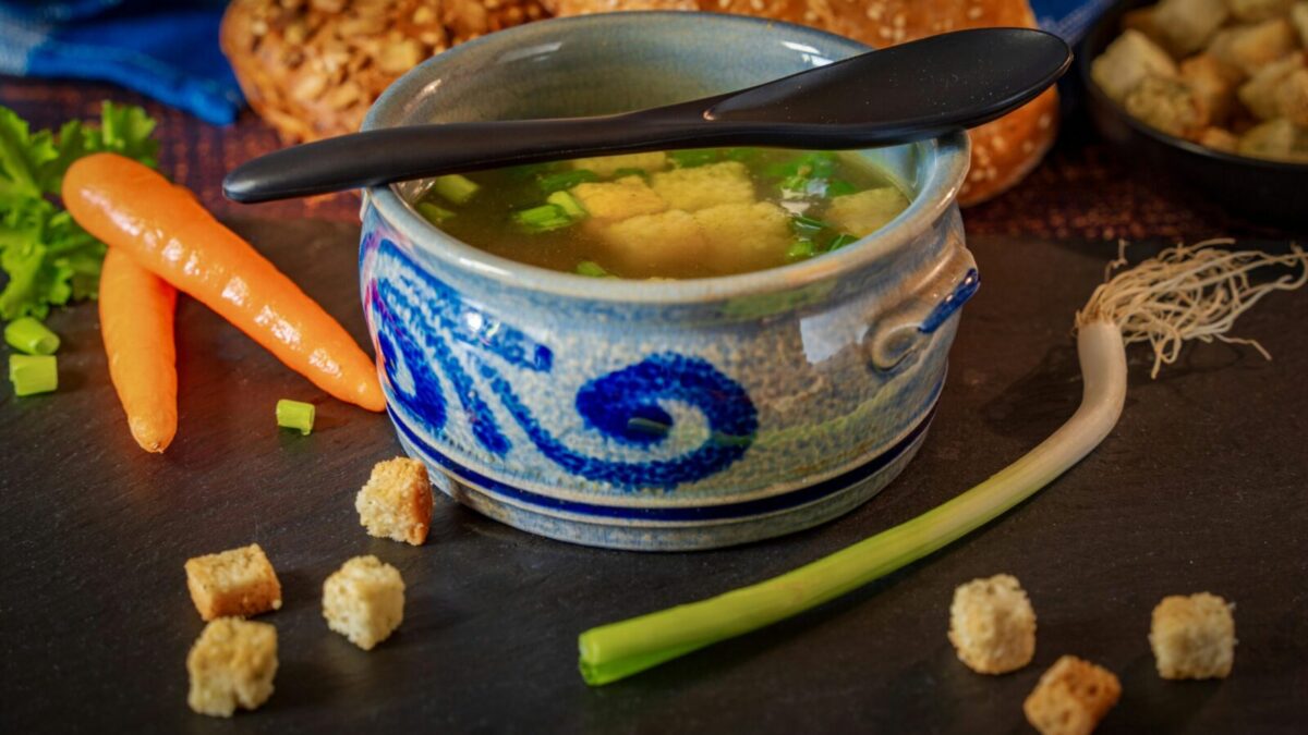 A comforting bowl of vegetable broth with fresh carrots, leeks, and croutons, perfect for a cozy meal.