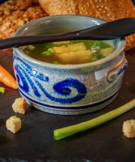 A comforting bowl of vegetable broth with fresh carrots, leeks, and croutons, perfect for a cozy meal.