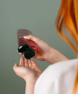 Woman pressing shampoo from a bottle into her hand, highlighting hair care routine.