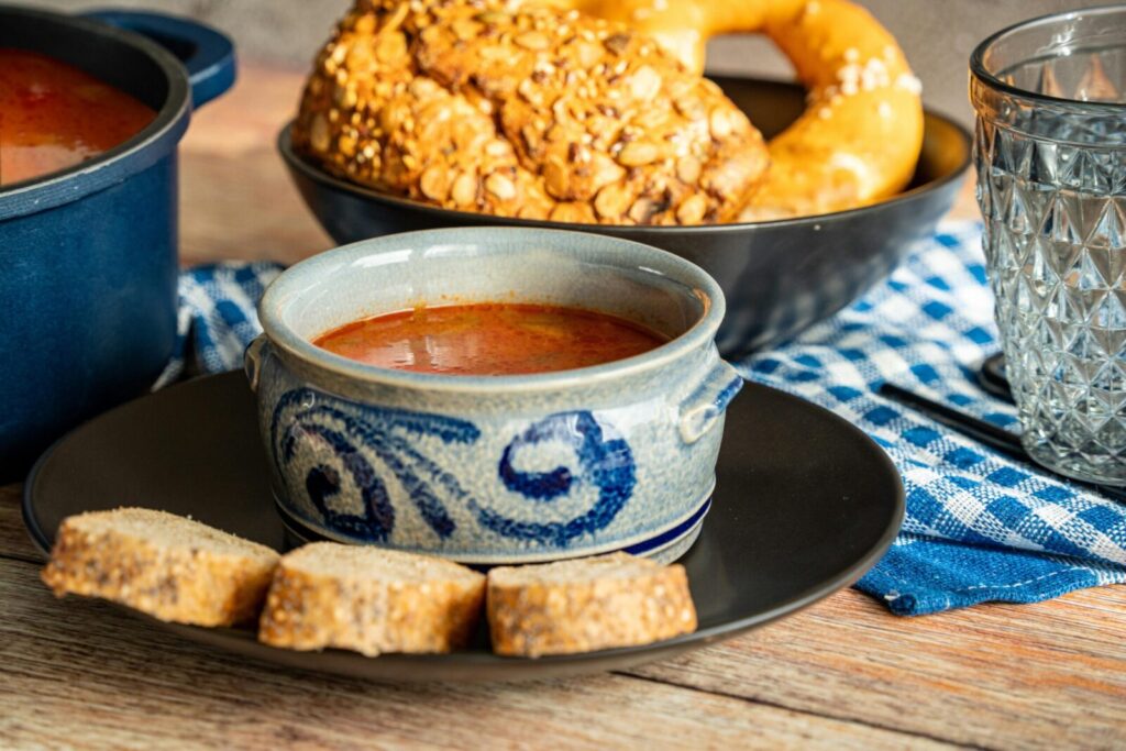 A classic Eastern European soup served with bread and pretzel, offering a hearty home-cooked meal.