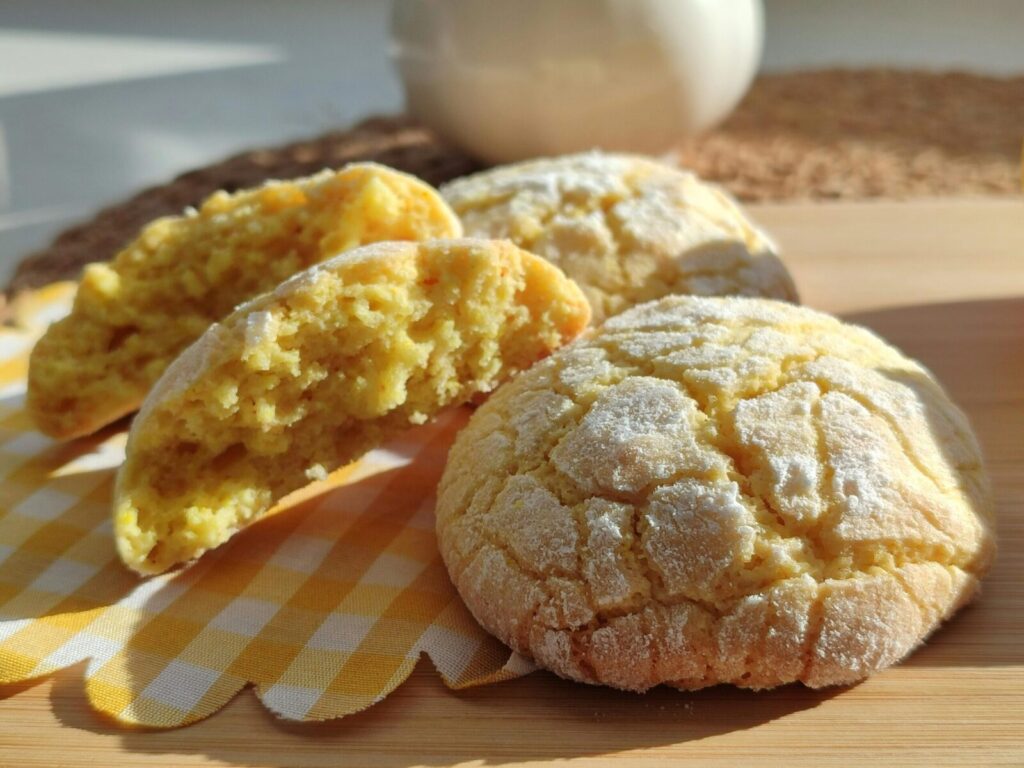 Close-up of freshly baked lemon cookies on a checkered cloth, sunlight accentuating texture.