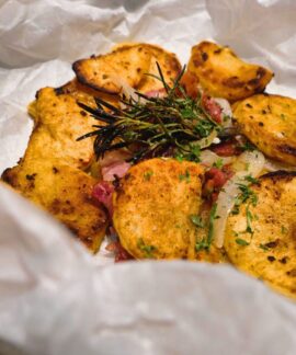Delicious rustic-style baked potato slices with fresh herbs on parchment paper.