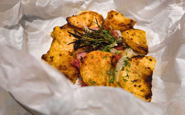 Delicious rustic-style baked potato slices with fresh herbs on parchment paper.