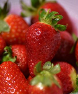Close-up of ripe, vibrant red strawberries in a colander with green stems.