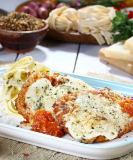 Tasty chicken parmesan with pasta and fresh ingredients on a rustic table.