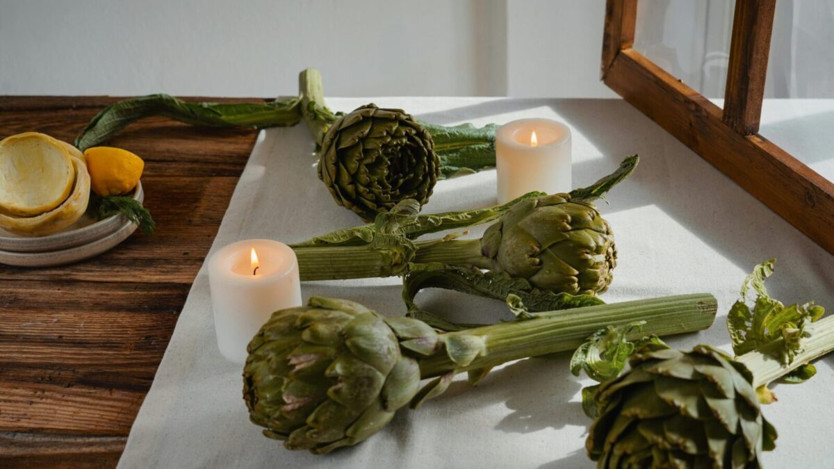 Artichokes on a rustic table with candles create an inviting and warm atmosphere.