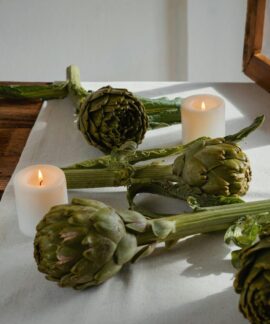 Artichokes on a rustic table with candles create an inviting and warm atmosphere.