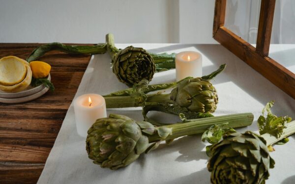 Artichokes on a rustic table with candles create an inviting and warm atmosphere.