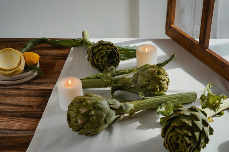 Artichokes on a rustic table with candles create an inviting and warm atmosphere.