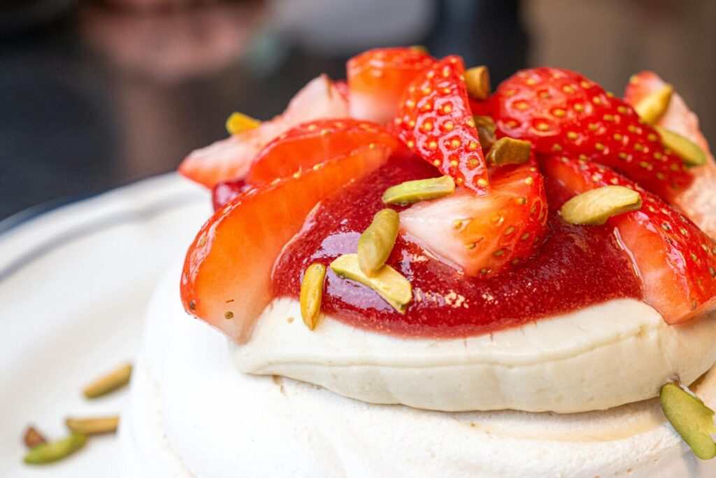 Close-up of a pavlova topped with fresh strawberries and pistachios, perfect for gourmet breakfast ideas.