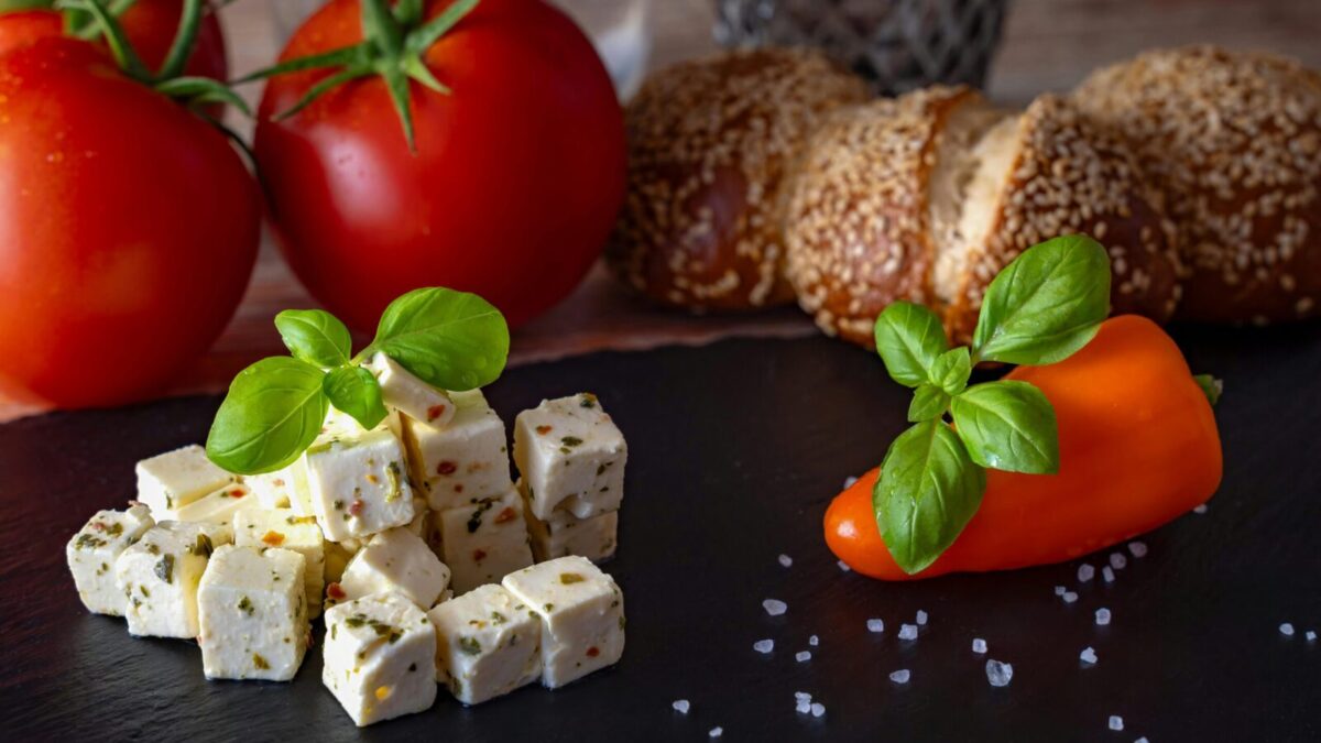 A delicious Mediterranean platter featuring feta, tomatoes, bread, and peppers.