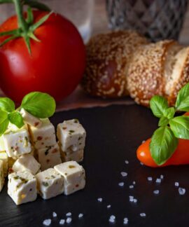 A delicious Mediterranean platter featuring feta, tomatoes, bread, and peppers.