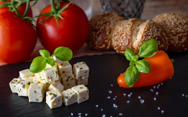 A delicious Mediterranean platter featuring feta, tomatoes, bread, and peppers.