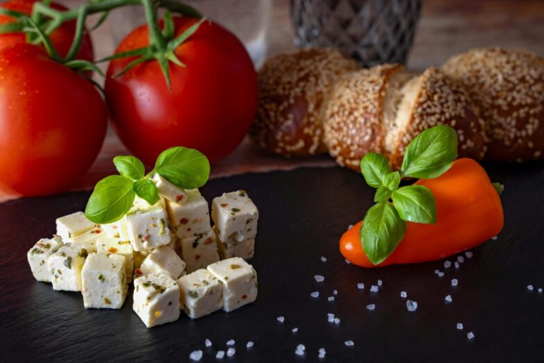 A delicious Mediterranean platter featuring feta, tomatoes, bread, and peppers.