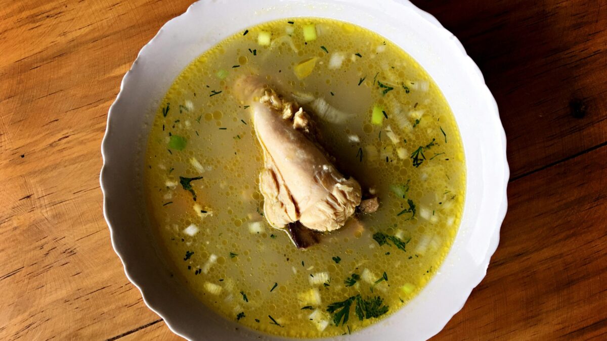 Delicious Ecuadorian chicken soup with vegetables in a white bowl, perfect for a comforting meal.