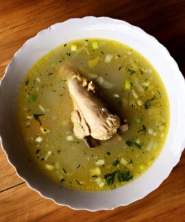 Delicious Ecuadorian chicken soup with vegetables in a white bowl, perfect for a comforting meal.
