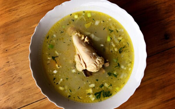 Delicious Ecuadorian chicken soup with vegetables in a white bowl, perfect for a comforting meal.