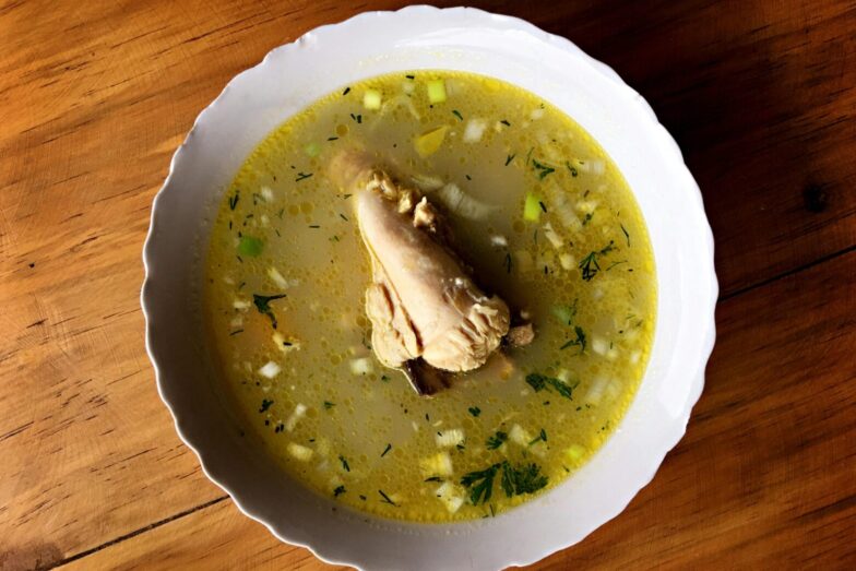 Delicious Ecuadorian chicken soup with vegetables in a white bowl, perfect for a comforting meal.