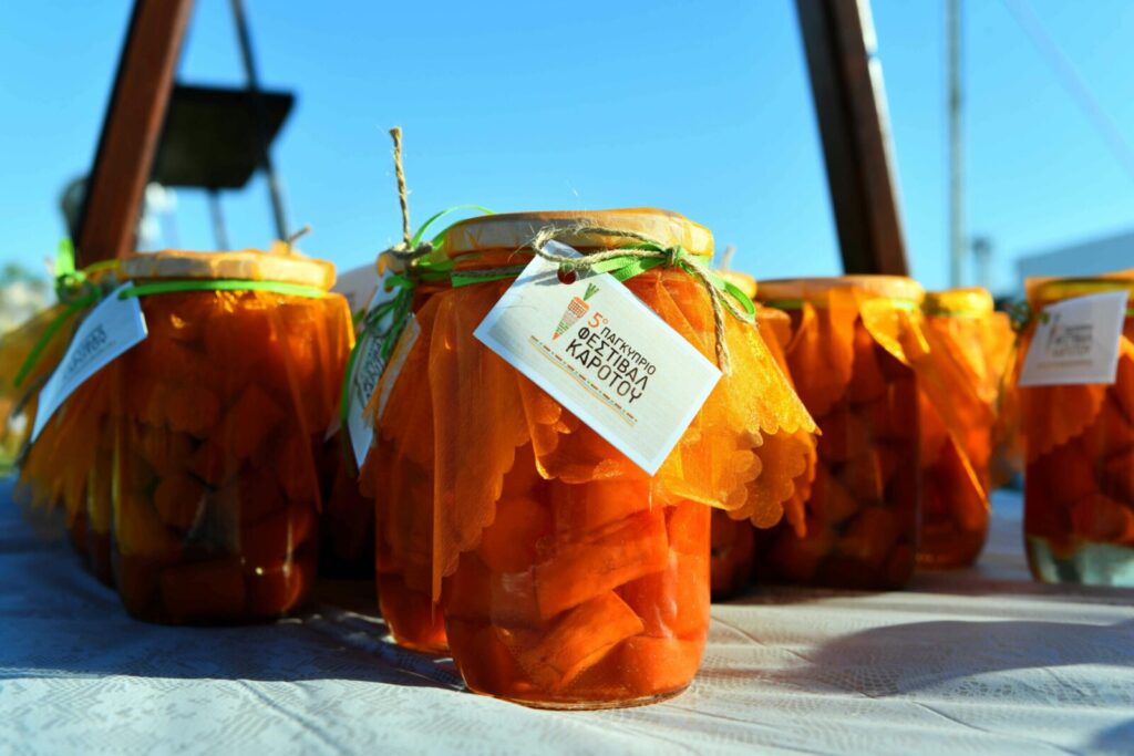 Colorful jars of carrot preserves displayed outdoors with decorative fabric lids.