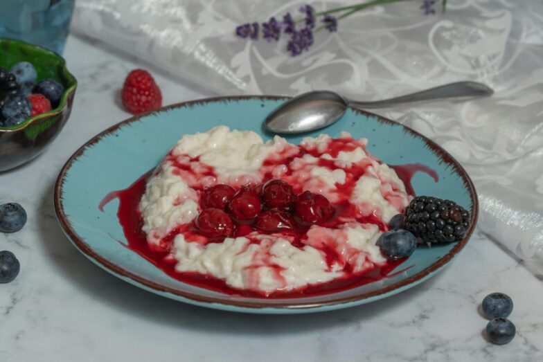 A delectable rice porridge with fresh berries and cherry sauce on a ceramic plate.