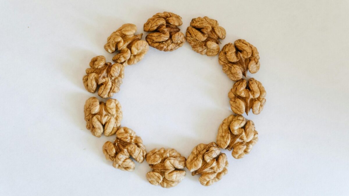 Top view of walnuts arranged in a circle on a white background, showcasing texture.