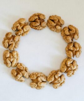 Top view of walnuts arranged in a circle on a white background, showcasing texture.