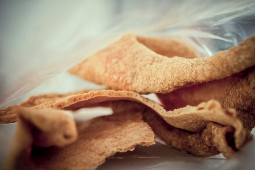 Close-up image of crunchy, golden brown pork rind snack, showcasing texture and detail.