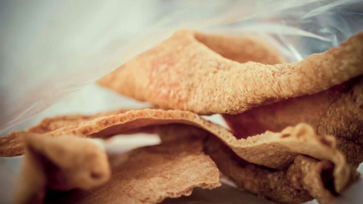 Close-up image of crunchy, golden brown pork rind snack, showcasing texture and detail.