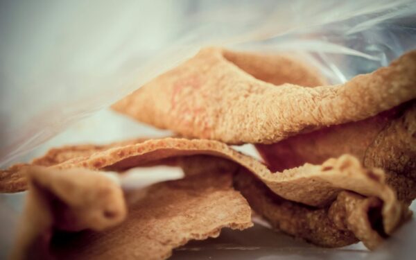 Close-up image of crunchy, golden brown pork rind snack, showcasing texture and detail.