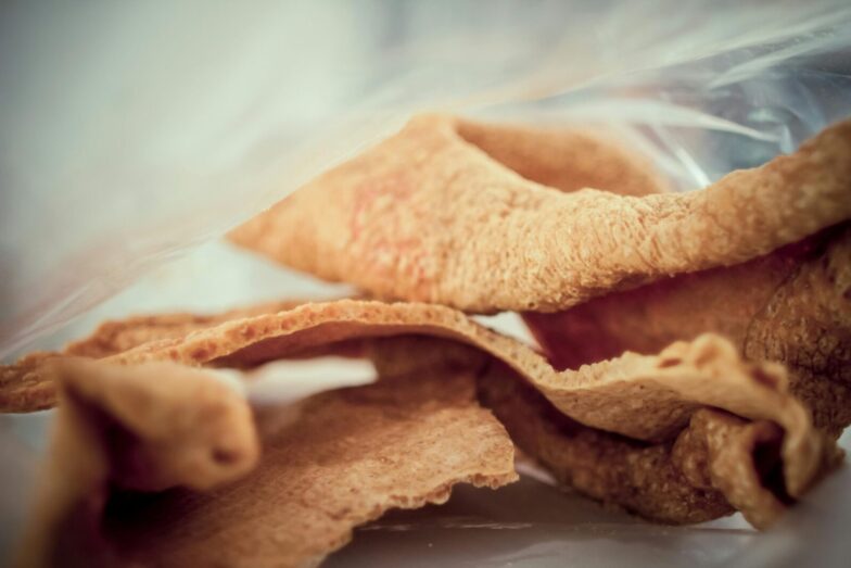 Close-up image of crunchy, golden brown pork rind snack, showcasing texture and detail.