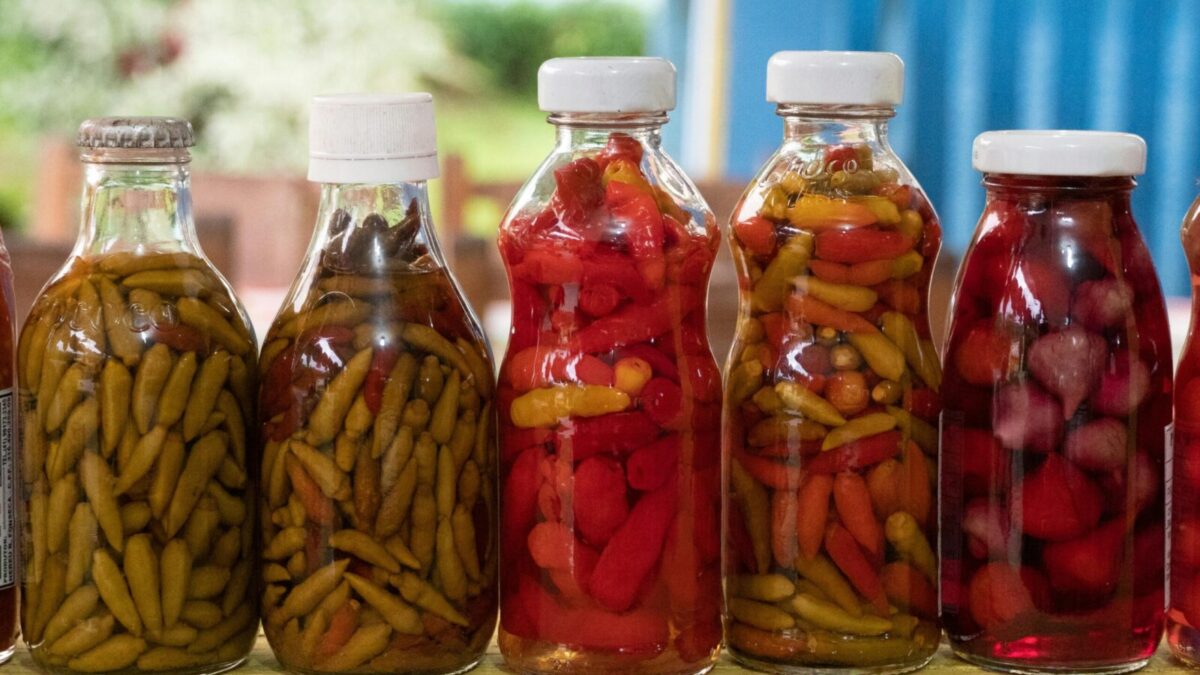 Close-up of vibrant pickled peppers in glass bottles captured in Morretes, Brazil.
